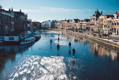 People on river amidst buildings in city