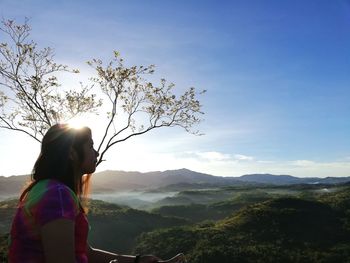 Side view of thoughtful woman looking at mountains against sky