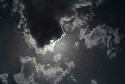 Low angle view of power lines against cloudy sky