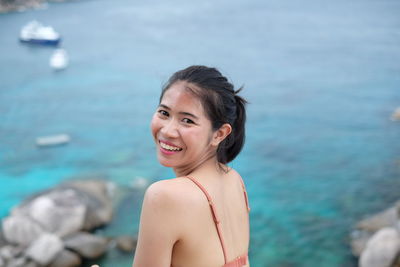 Portrait of young woman standing against sea