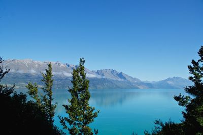 Scenic view of lake and mountains against clear blue sky