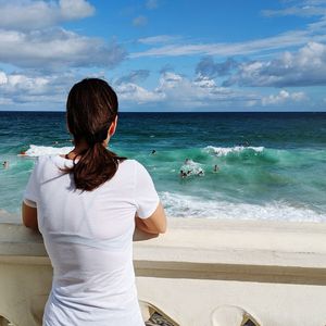 Rear view of man looking at sea against sky