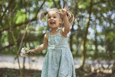 Portrait of young woman standing against trees