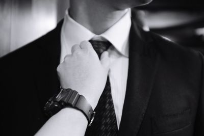 Midsection of businessman adjusting necktie