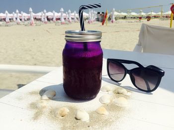 Close-up of drink by sunglasses on table at beach