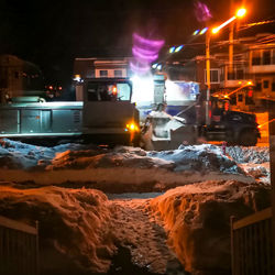 Illuminated street amidst buildings in city at night