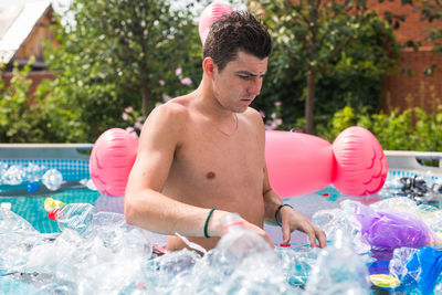 Full length of shirtless man holding swimming pool