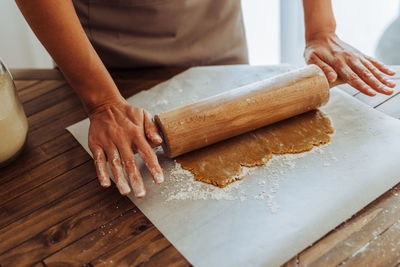 Close up of hands rolling dough for cookies at table