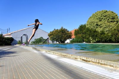 Full length of woman jumping on a swimming pool