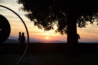 Silhouette man standing by tree against sky during sunset