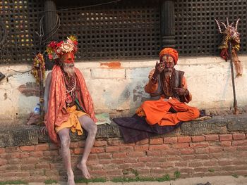 Sadhus sitting against building