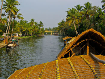 Scenic view of palm trees by canal against sky