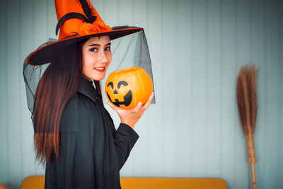 Portrait of a smiling young woman standing by pumpkin