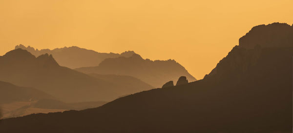 Scenic view of silhouette mountains against orange sky