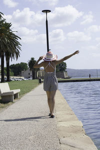 Rear view of woman standing by umbrella against sky