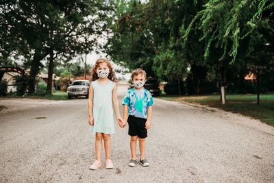 Two young kids standing outside wearing homemade fabric masks