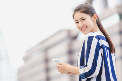 Portrait of smiling young woman using mobile phone