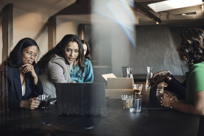 Businesswomen conducting meeting over laptop at desk in office