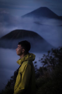 Side view of man looking away against sky