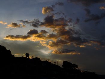 Silhouette of trees against cloudy sky