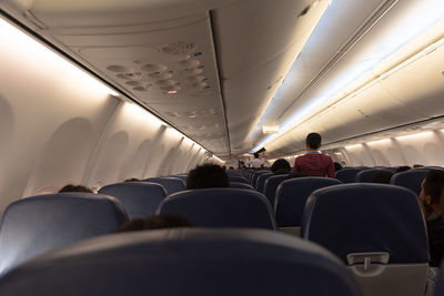 Rear view of people in illuminated airplane