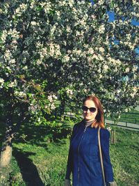 Young woman standing by tree in park