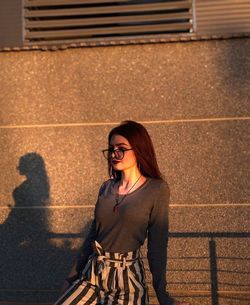 Portrait of smiling young woman standing against wall