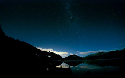 Scenic view of lake and mountains against sky at night