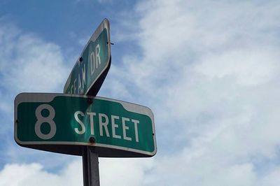 Low angle view of road sign against cloudy sky