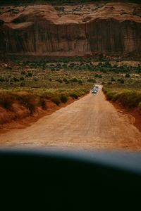 Dirt road passing through desert seen through windshield