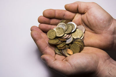 Close-up of hands holding coins on white background