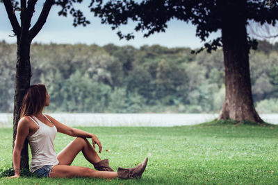 Young woman sitting on grassy field at park