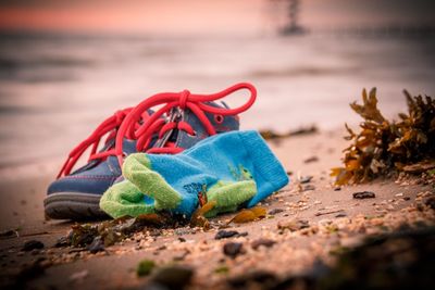 Close-up of shoes and socks on sand at beach