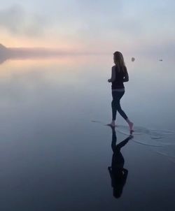 Full length of woman standing in sea against sky