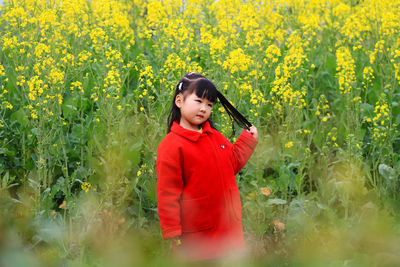 Cute girl standing against yellow flowering plants