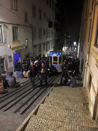 People on street amidst buildings in city at night