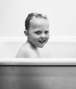 Side view portrait of smiling boy bathing in bathtub at home