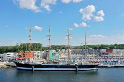 Boats moored at harbor against sky in city