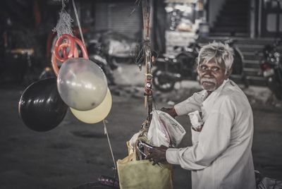 Man holding balloons hanging in city
