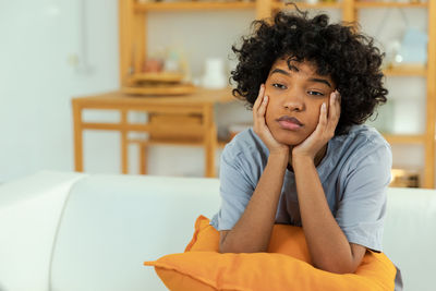 Portrait of young woman sitting on sofa at home