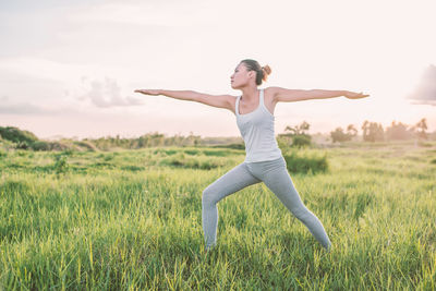 Young woman exercising on grassy field