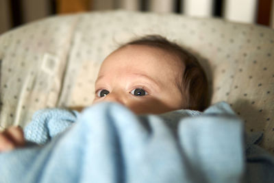 Close-up of cute baby lying on bed