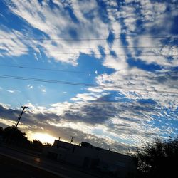 Low angle view of bird flying against cloudy sky