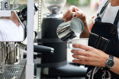 Midsection of woman drinking coffee in gym