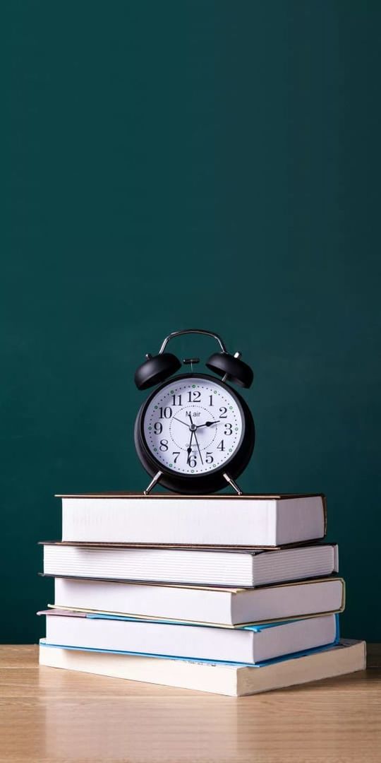 clock, time, publication, book, education, indoors, watch, table, no people, learning, alarm clock, copy space, desk, clock face, still life, studio shot, blue, deadline, furniture, school, number, instrument of time, interior design