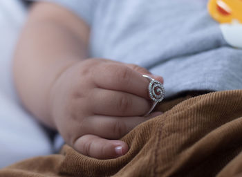 Midsection of baby holding ring