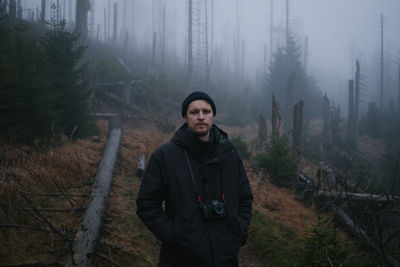 Portrait of young man standing in forest