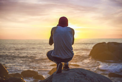 Rear view of man standing on rock at beach