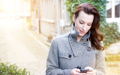 Close-up of woman using mobile phone while standing on footpath