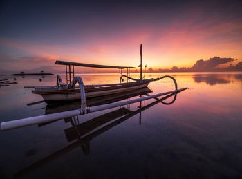 Boat moored in sea against sky during sunset